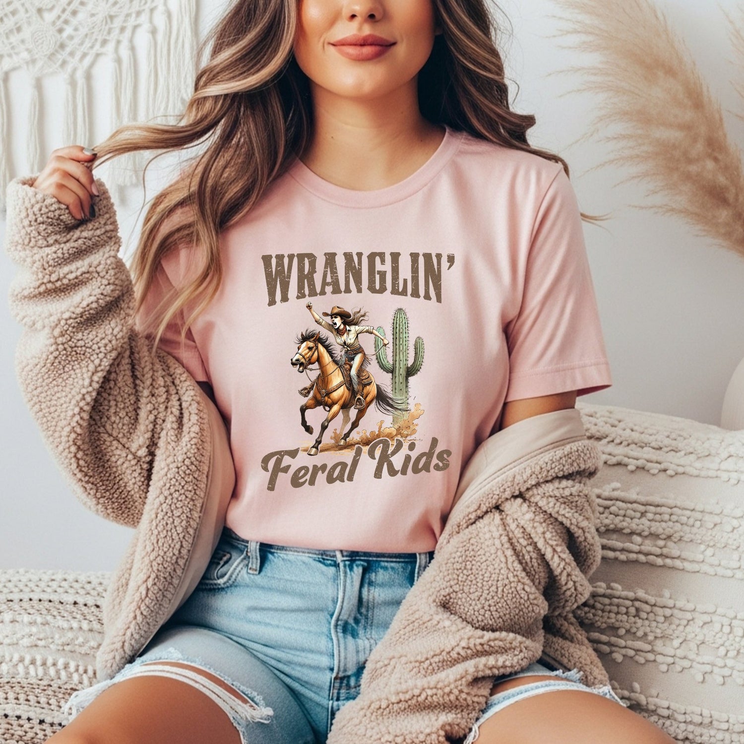 Graphic pink shirt with cowgirl design and playful feral kids parenting humor