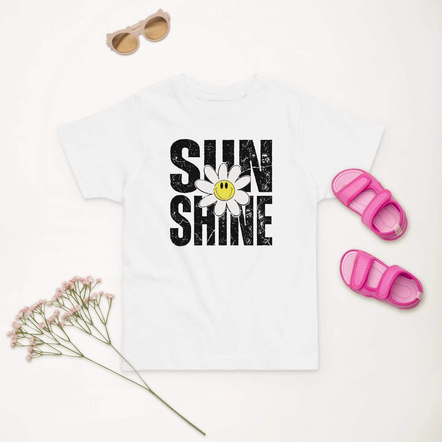 white toddler tee that says sunshine with a smiling daisy
